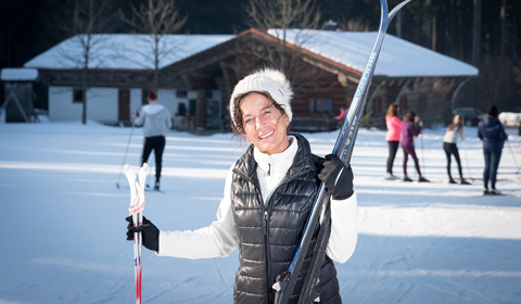 Eine Frau steht im Schnee und hält Skier in der Hand, bereit für ein Abenteuer im Winter.